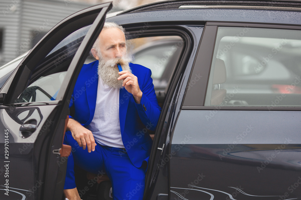 Old stylish man in the luxury car. Male with beard and mustash driving automobile. car sales salon.