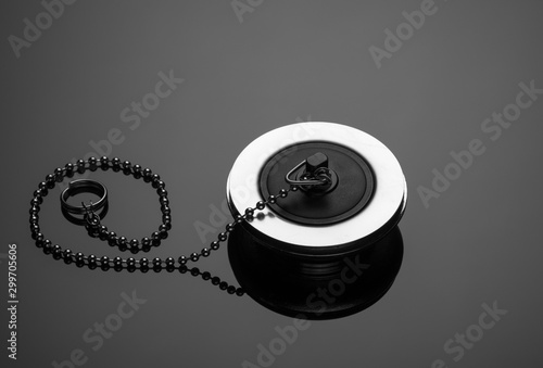 close-up of bath and sink stopper with long chain of silver-colored metal and plastic on dark glass surface photo