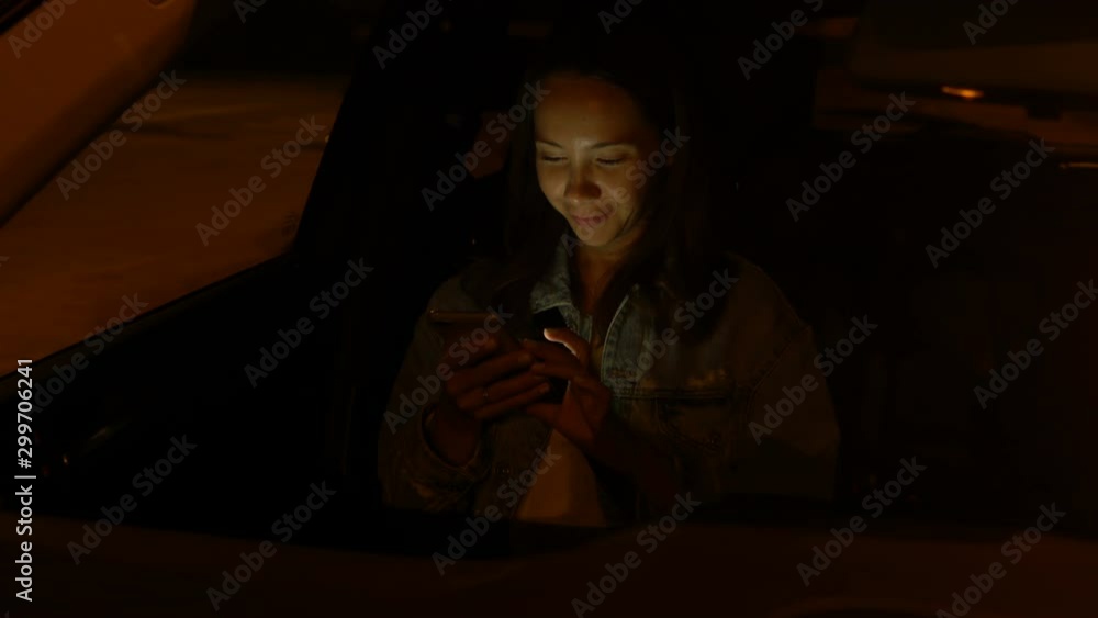 Young woman using mobile phone while sitting in a car at night Young woman using mobile phone while sitting in a car at night