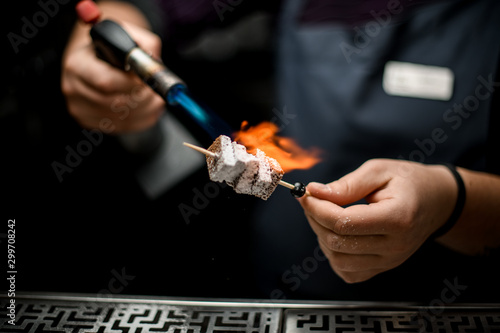 Wallpaper Mural Male bartender toasing a brownie pieces on the skewer with a burner Torontodigital.ca