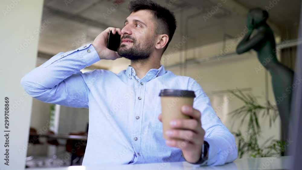 Young manager talking on the phone while drink coffee in the modern office Young manager talking on the phone while drink coffee in the modern office