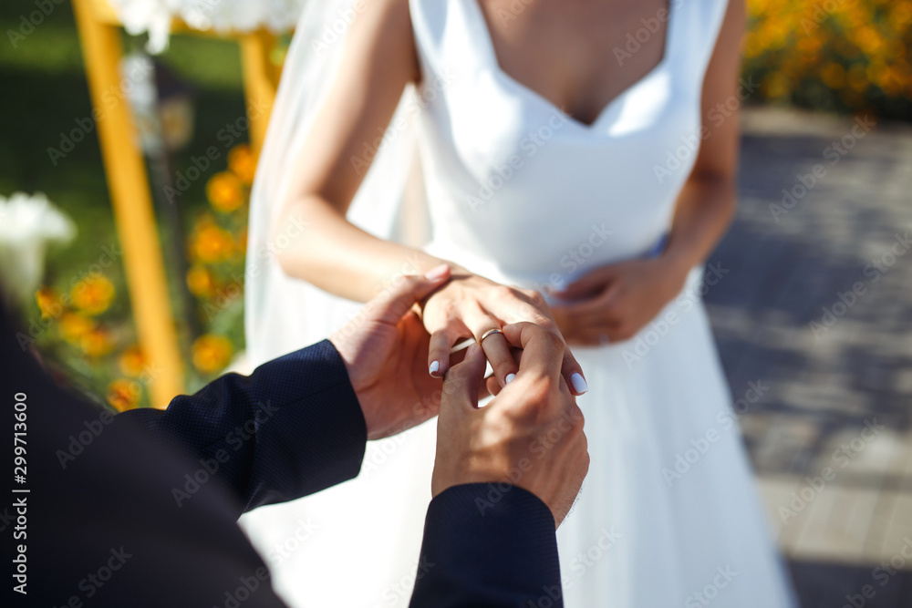 Fototapeta premium Wedding engagement rings. Newlywed couple's hands with engagement rings. Young couple at ceremony. Bride and groom with engagement rings. Сeremony wedding day. Concept weddings details.