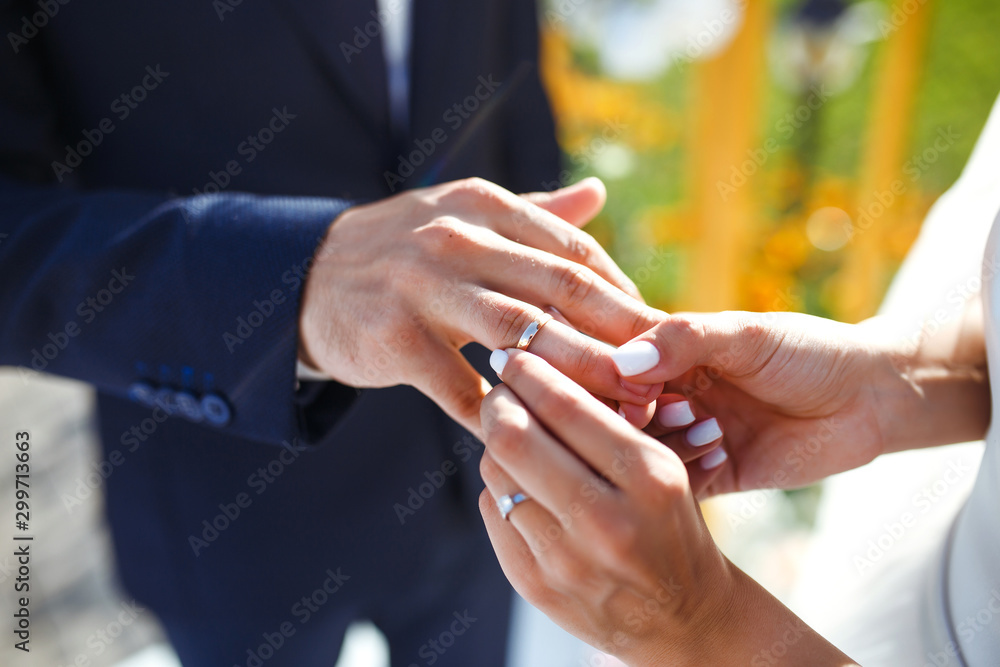 Fototapeta premium Wedding engagement rings. Newlywed couple's hands with engagement rings. Young couple at ceremony. Bride and groom with engagement rings. Сeremony wedding day. Concept weddings details.