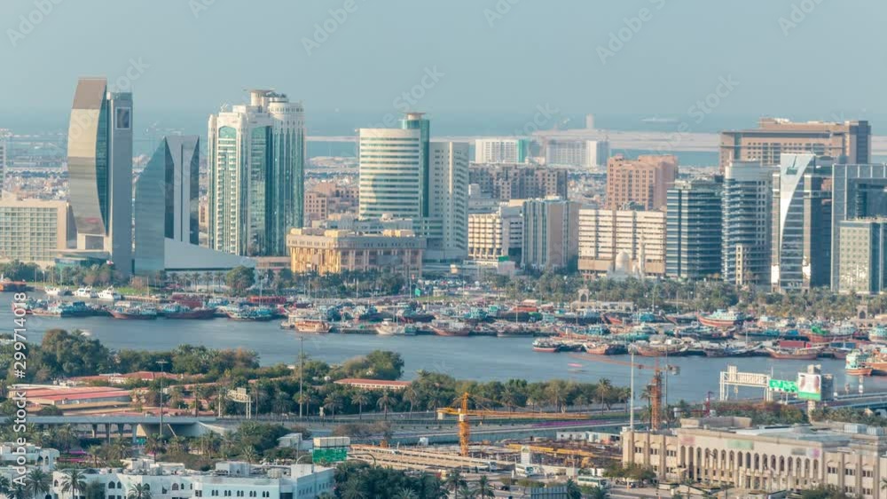 Aerial view of new modern skyscrapers Timelapse near river with wooden ships on a sunny day with blue sky in Deira, Dubai, United Arab Emirates Aerial view of new modern skyscrapers Timelapse near river with wooden ships on a sunny day with blue sky in Deira, Dubai, United Arab Emirates