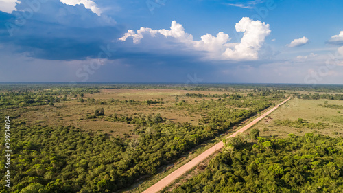 Canvas Print Aerial view with rain clouds an blue sky of Transpantaneira dirt road crossing t