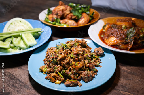 Spicy food in wood table such as Duck minced salad, Deep fried chicken, Stir fried fish with red chili paste on wood table. Thai traditional yummy food style dining table.