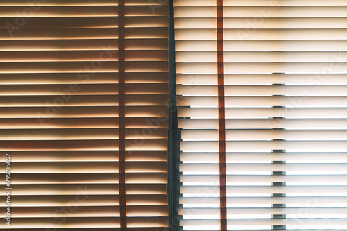 Brown wooden blinds with daylight illuminating through.