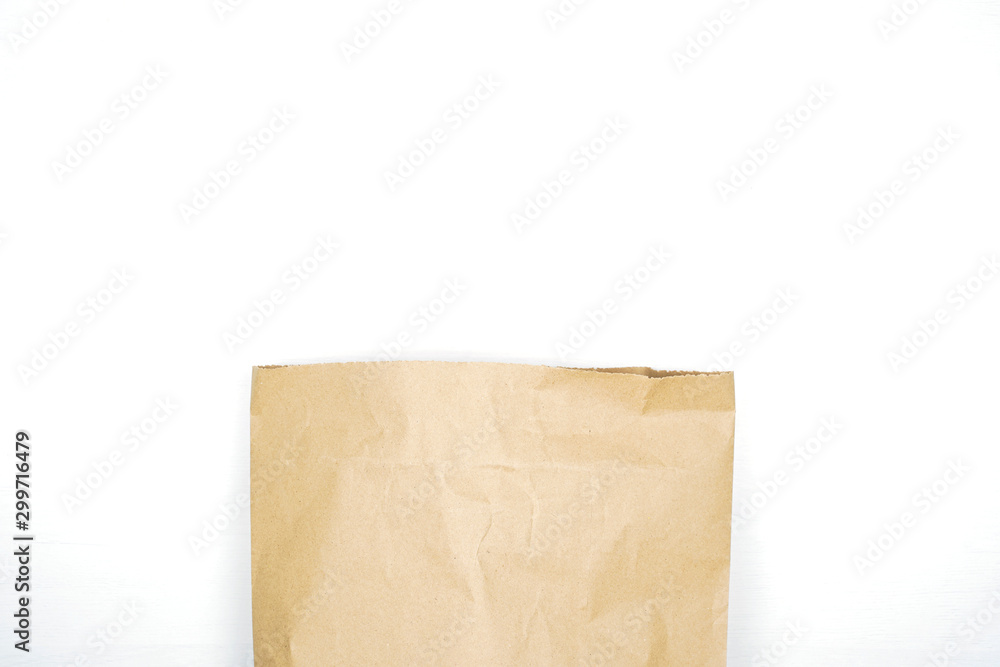 Brown paper bag on wooden white background with empty space for text. Flat lay, top view.