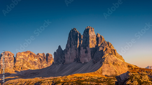 Panoramic view over beautiful sunset in magical Three Dolomite peaks at the national park Three Peaks (Tre Cime, Drei Zinnen) in Autumn October colors at blue sky, South Tyrol, Italy