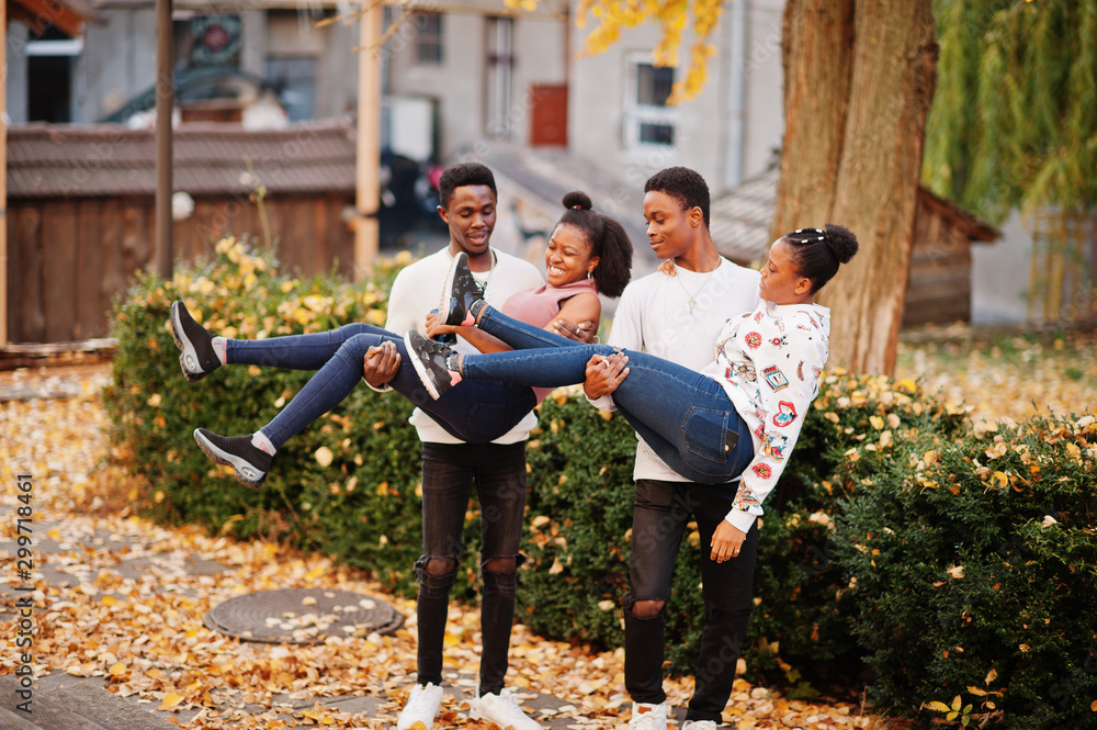 Fototapeta premium Four african friends walking the streets of an ancient city at autumn sunny day.