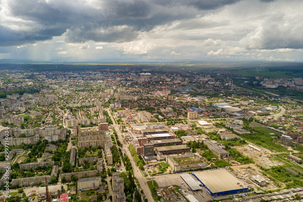 Aerial view of town or city with rows of buildings and curvy streets in summer. Urban landscape from above.