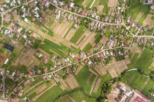 Wallpaper Mural Top down aerial view of town or village with rows of buildings and curvy streets between green fields in summer. Countryside landscape from above. Torontodigital.ca