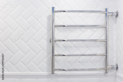 Heated towel rail with side connection in a white brick tiled bathroom.