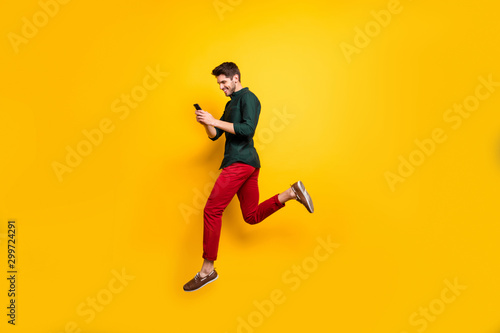 Profile side full length body size photo of cheerful positive man running jumping addicted to his cellphone aspiring for sales isolated bright color background