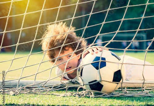 Soccer ball in goal on green grass. Disappointed football team goalkeeper following goals. Goalkeeper emotionally reacts after missed goal during game. Defeat Concept. selective focus