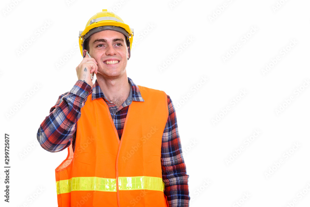 Happy young man construction worker thinking while talking on the phone Happy young man construction worker thinking while talking on the phone