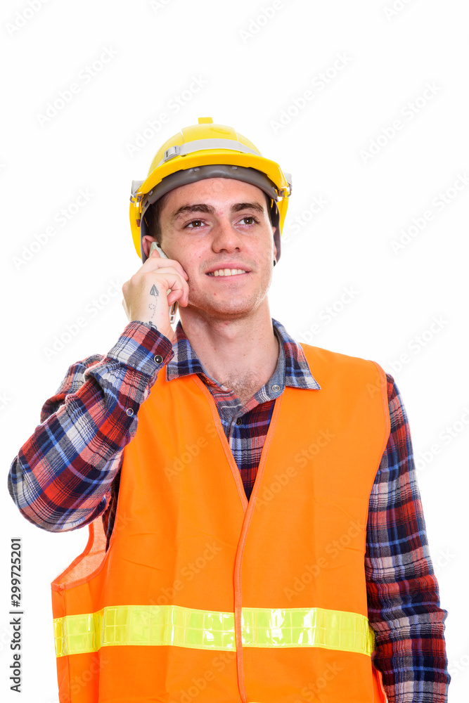 Happy young man construction worker thinking while talking on the phone