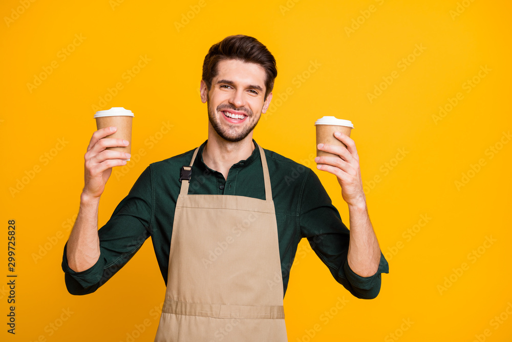 Photo of cheerful white positive toothy beaming barista hold green shirt two disposable paper cups of tea and coffee for you to choose isolated vibrant color background Photo of cheerful white positive toothy beaming barista hold green shirt two disposable paper cups of tea and coffee for you to choose isolated vibrant color background