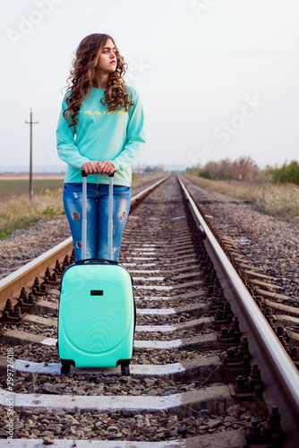 girl on railway. Girl tourist with a suitcase on a railway platform. Autumn train ride. Railway in the fall. Girl with a suitcase by the railway. Turquoise suitcase
