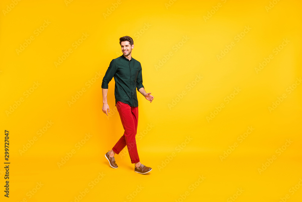 Turned full length body size photo of positive cheerful handsome guy walking towards empty space with cheerful smile isolated over vibrant color background Turned full length body size photo of positive cheerful handsome guy walking towards empty space with cheerful smile isolated over vibrant color background