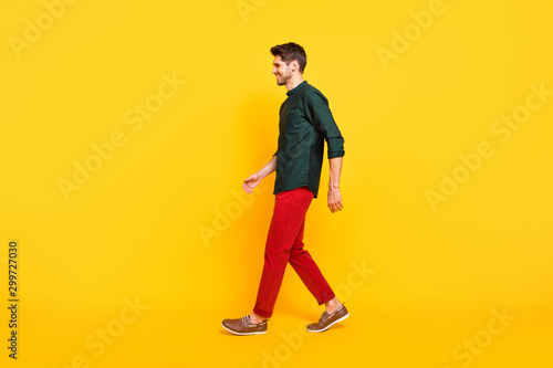 Full body profile side photo of cheerful positive brunette hair guy go walk have spring weekends holidays enjoy wear youth style clothing sneakers isolated over yellow color background