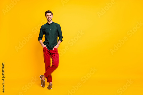 Full length body size photo of posing cheerful toothy worker standing confidently with hands in pockets and legs crossed isolated over yellow vibrant color background