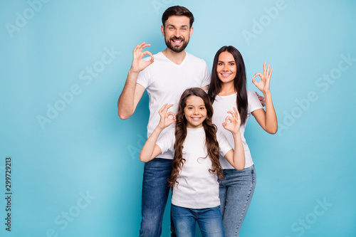 Portrait of positive content three promoters mom dad offspring with brunet hair show ok sign recommend sales ads wear white t-shirt denim jeans isolated over blue color background