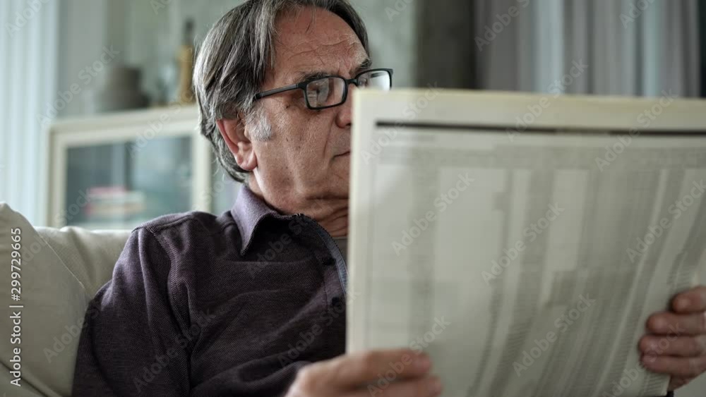 Senior man reading newspaper at home Senior man reading newspaper at home