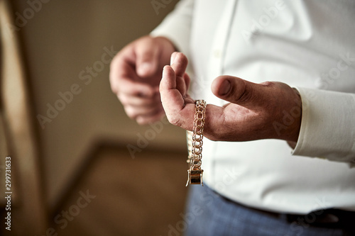 Gold bracelet on the man's hand, male hands closeup,groom getting ready in the morning before wedding ceremony