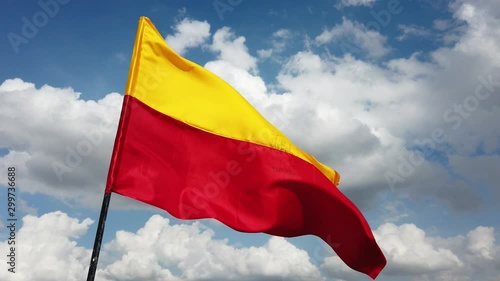Close up of the official flag of the South Indian state of Karnataka flying against the sky and clouds in the background