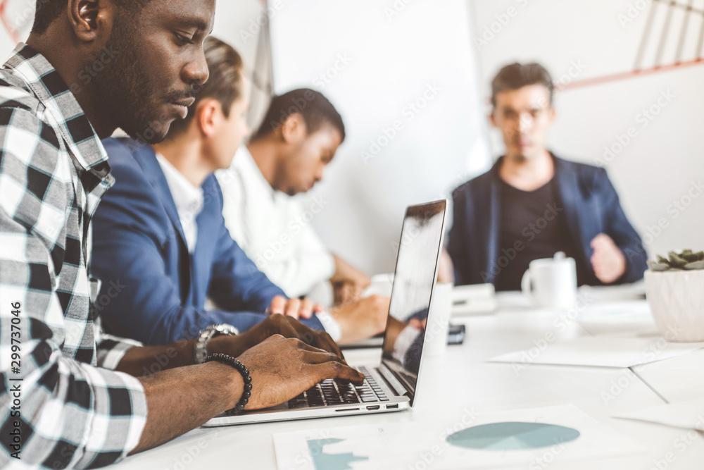 A team of young office workers, businessmen with laptop working at the table, communicating together in an office. Corporate businessteam and manager in a meeting. coworking. A team of young office workers, businessmen with laptop working at the table, communicating together in an office. Corporate businessteam and manager in a meeting. coworking.