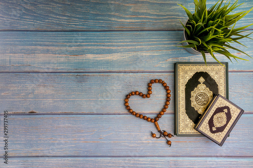 Fotografija Flat lay view of vase, tasbih or rosary beads and Holy book of Al Quran with arabic calligraphy meaning of Al Quran over wooden background