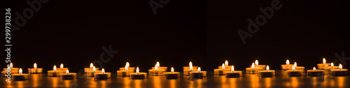 Vászonkép Burning golden candles on black background