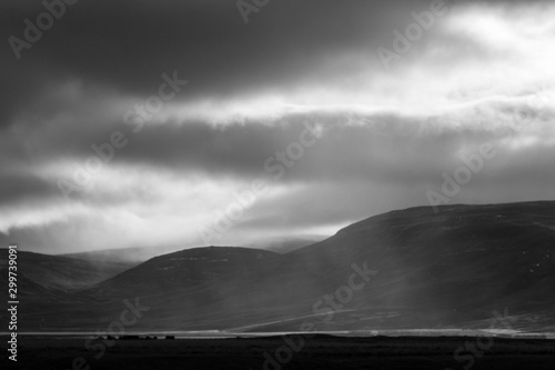 Sunlight penetrates through the clouds and illuminates a rain shower over the Svinadalur at Búðardalur in western Iceland.