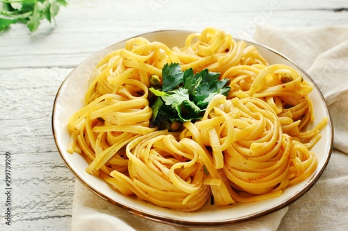 Pasta in a beautiful white plate. Pasta on a light wooden background. Spaghetti with parsley leaves. Macaroni  parsley  lemon  sweet yellow pepper.