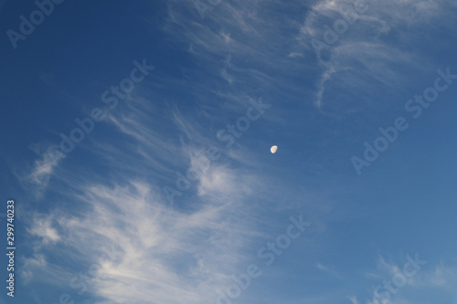 Blue sky with light white transparent clounds and big moon air background