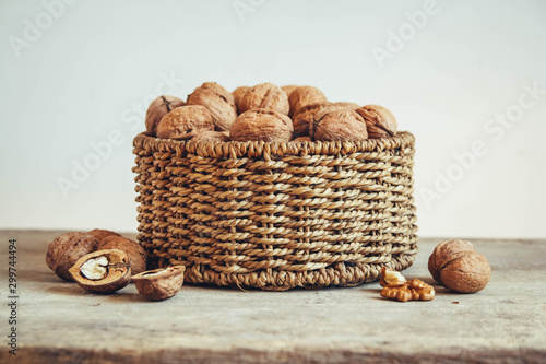 Walnuts in a round wicker basket on a wooden background. Place for your text