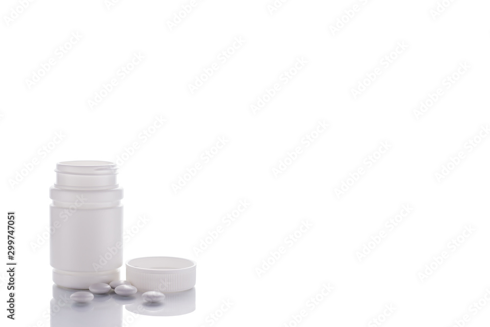 A vial of pills stands on a mirror surface on a white background on the left with a place for text. A vial of pills stands on a mirror surface on a white background on the left with a place for text.