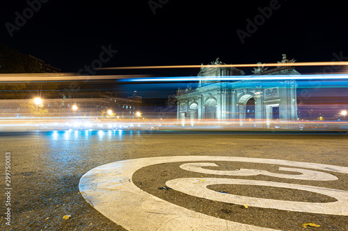 Night view of Puerta de Alcala with traffic lights in Madrid, Spain. Copy space available and 30 km per hour urban limit sign.