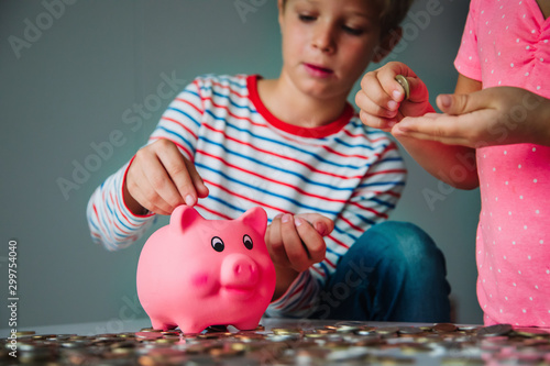 boy and girl saving money, kids put coins into piggy bank
