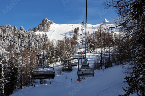Skiers and snowboarders using a сhairlift at Ischgl ski resort in Tyrol Austria in winter Alps. Sunny day with crisp white snow on slopes