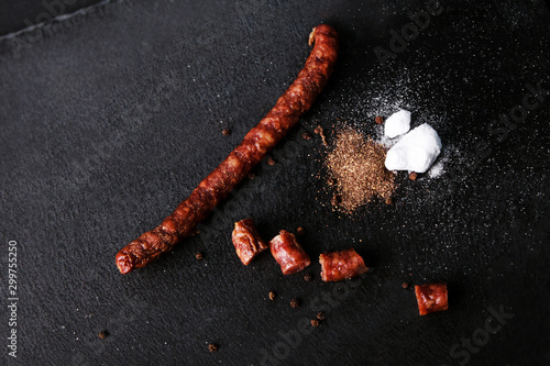 sausage with spices on black background, top view