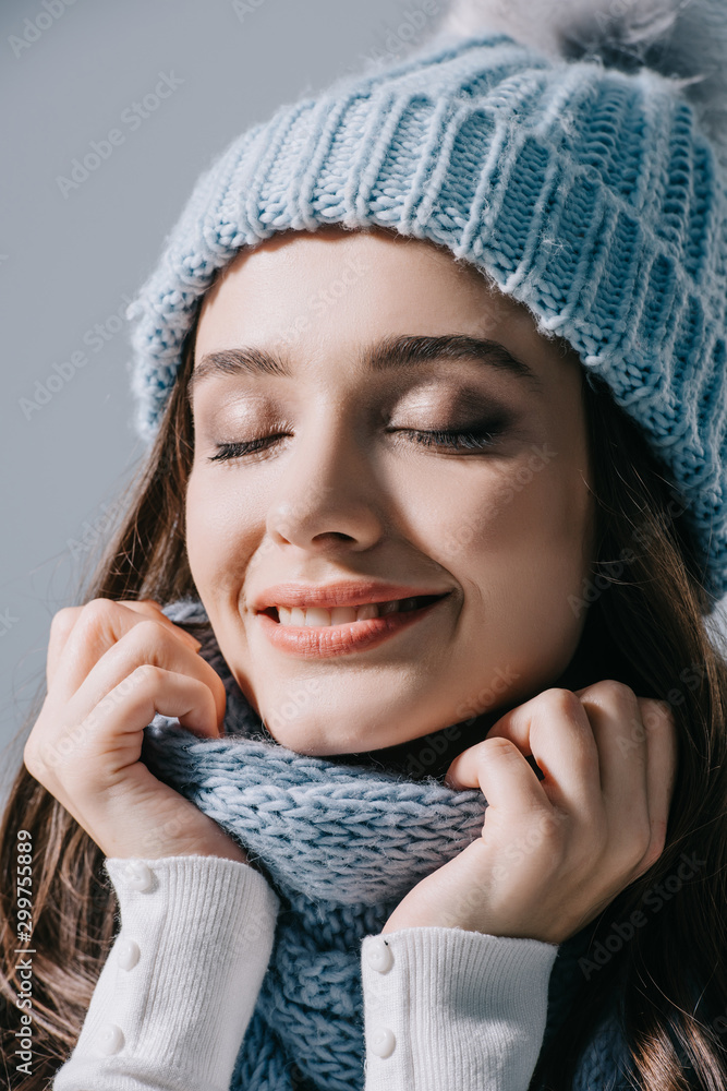 beautiful dreamy woman posing with closed eyes in knitted hat and scarf, isolated on grey beautiful dreamy woman posing with closed eyes in knitted hat and scarf, isolated on grey