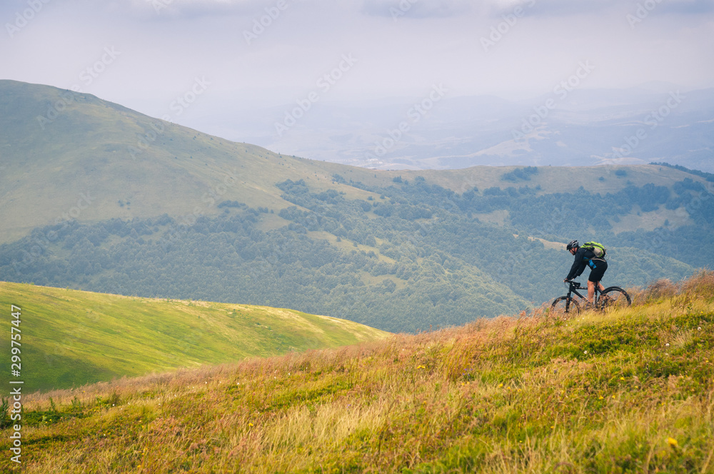 Beautiful mountain landscape with clouds. Tourist on a bicycle in the Carpathian mountains descends from the top of the Gimba.