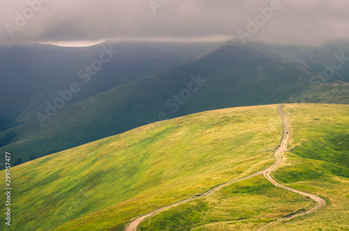 Beautiful mountain landscape with clouds. The road on the green top of Mount Ghimba in the Carpathians.