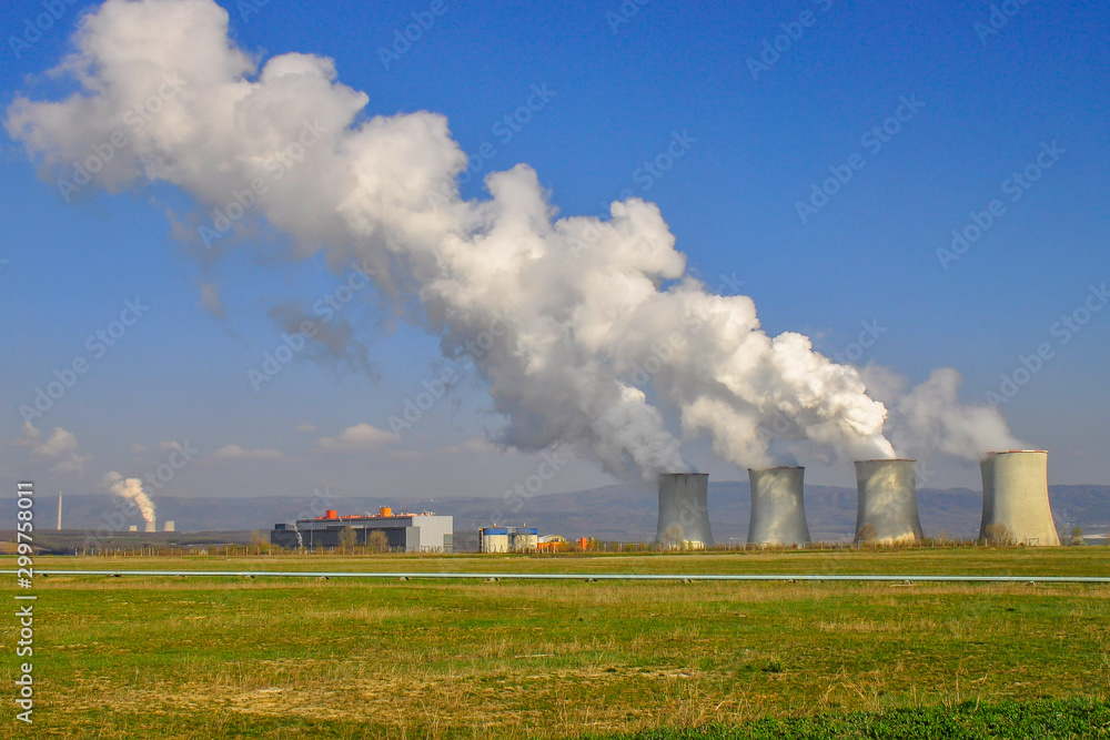 The Tusimice Power Stations. Smoking cooling towers of coal power plant. Heavy industrial coal powered electricity plant with smoke situated in countryside. Ore mountains in background. 