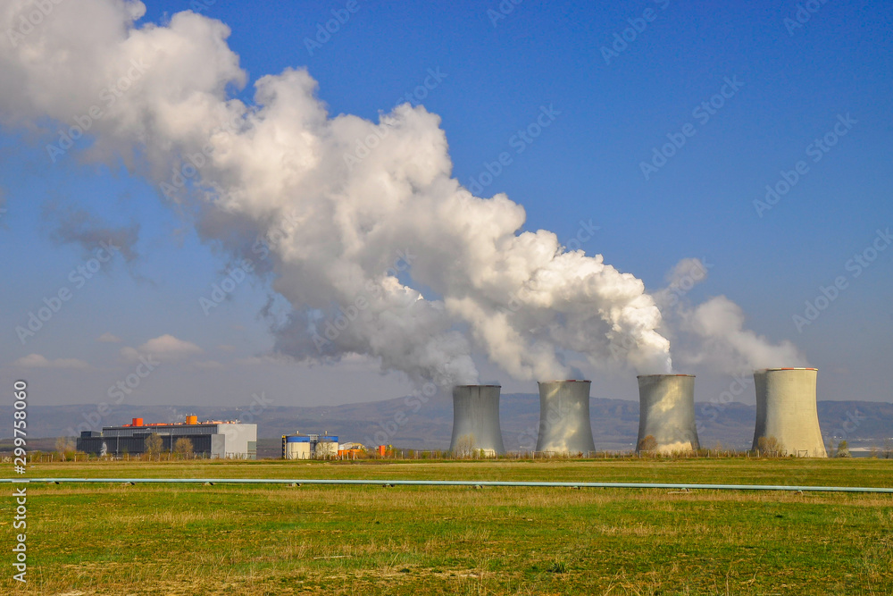 The Tusimice Power Stations. Smoking cooling towers of coal power plant. Heavy industrial coal powered electricity plant with smoke situated in countryside. Ore mountains in background. 