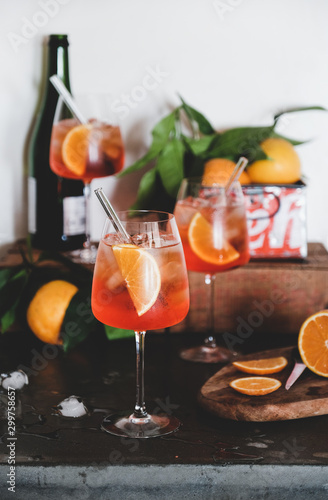 Fényképezés Aperol Spritz aperitif alcohol cold drink in glasses with straws with oranges and ice cubes on concrete table, white background, selective focus