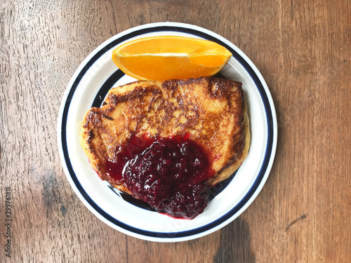 French toast with orange and red berries on white plate. Top view.