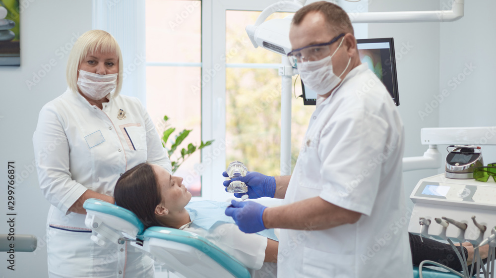 Fototapeta premium Doctor dentist treats teeth of a beautiful young girl patient. The girl on reception at the dentist. Doctor dentist treats tooth
